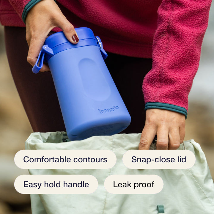 Blue LoonaGo being placed into a bag with feature labels: comfortable contours, snap-close lid, easy hold handle, and leak proof