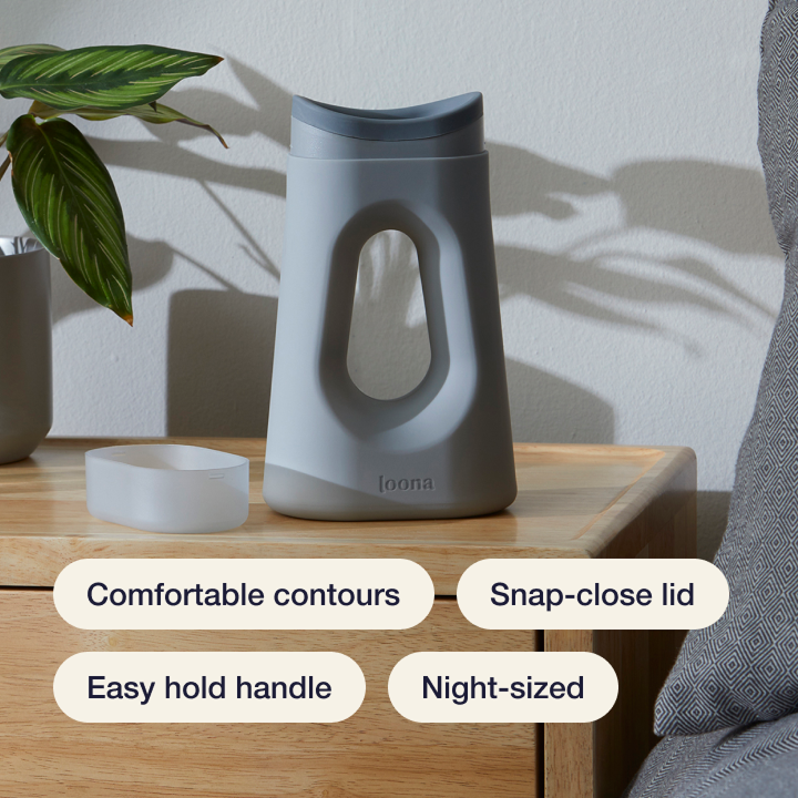 Gray Loona on a wooden nightstand with feature labels: comfortable contours, snap-close lid, easy hold handle, and night-sized