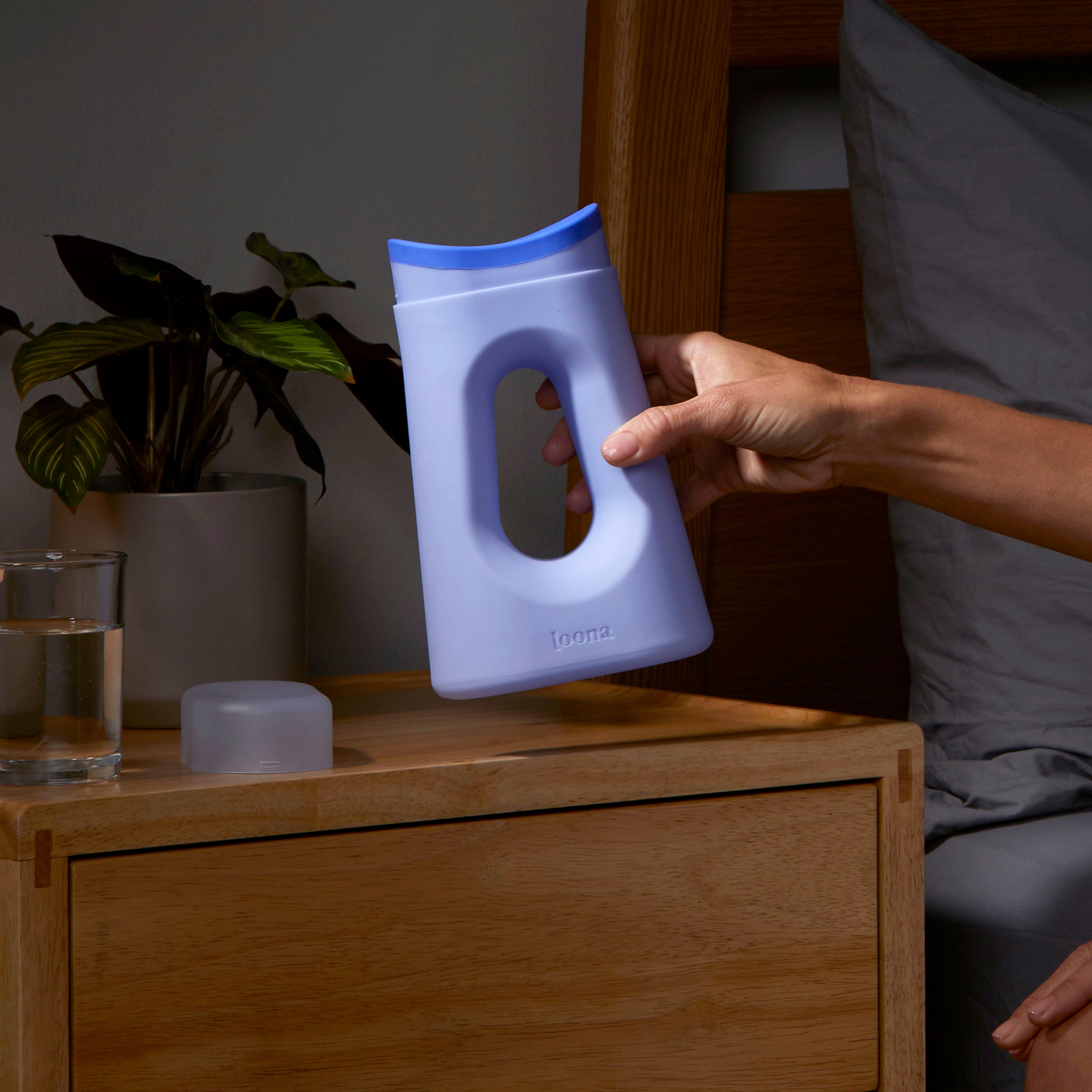 A woman's hand holds the Loona Female Urinal up to the camera demonstrating how easy it is to hold the comfortable handle
